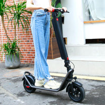 Donna in piedi con il monopattino elettrico HX X11 in una strada