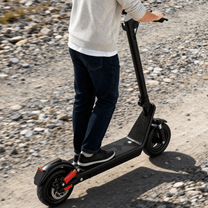 Uomo alla guida del monopattino elettrico HX X9B su una strada sterrata