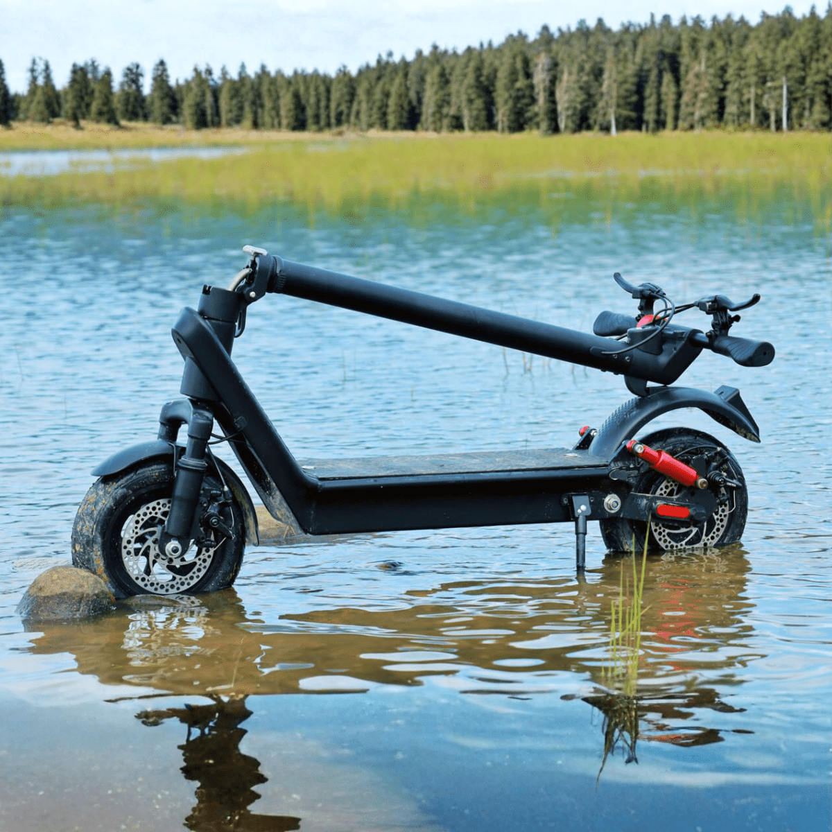 Monopattino elettrico HX X9B piegato in riva a un lago