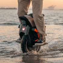 Persona alla guida del monociclo elettrico InMotion V12S in riva al mare