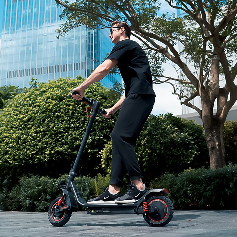 Persona alla guida del monopattino elettrico iScooter i10 Pro in città su un vialetto