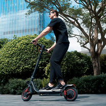 Persona alla guida del monopattino elettrico iScooter i10 Pro in città su un vialetto