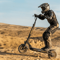 Pilota con il monopattino elettrico iScooter W9 Air in fuoristrada su terreno sabbioso