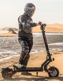 Persona in piedi con il monopattino elettrico KuKirin G2 Master con il casco su terreno sabbioso
