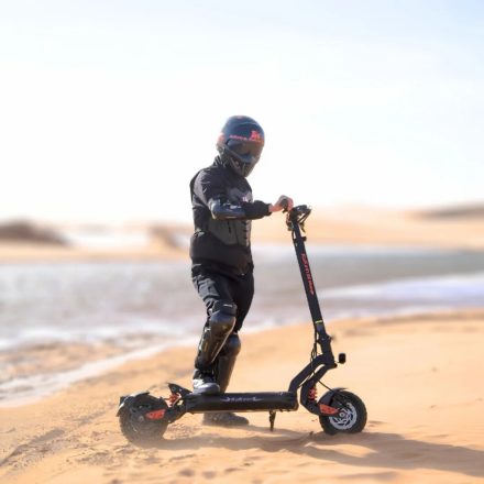Persona in piedi con il monopattino elettrico KuKirin G2 Master su terreno sabbioso