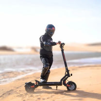 Persona in piedi con il monopattino elettrico KuKirin G2 Master su terreno sabbioso