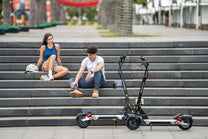 Persona seduta accanto al monopattino elettrico KuKirin M4 Max