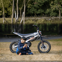 Persona seduta accanto alla moto da cross elettrica KuKirin X1 con un bambino