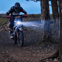 Moto da cross elettrica KuKirin X1 con le luci accese in un ambiente serale