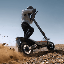 Pilota con il monopattino elettrico NAVEE XT5 Pro in fuoristrada su terreno sabbioso