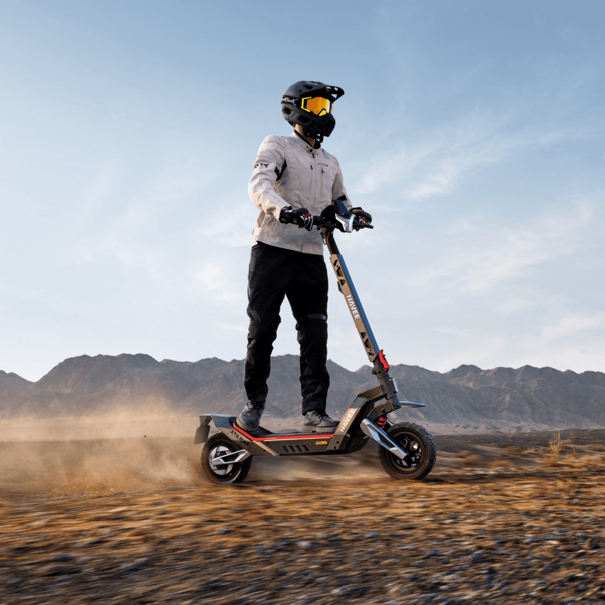 Persona in piedi con il monopattino elettrico NAVEE XT5 Pro su terreno sabbioso