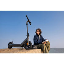 Persona seduta accanto al monopattino elettrico Segway Ninebot E2 Pro