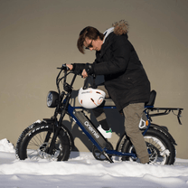 Uomo in piedi con la fat bike elettrica Onemile P40 Pro con il casco in un paesaggio invernale