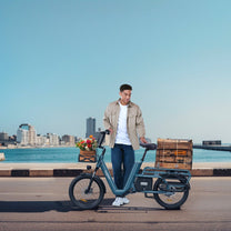 Uomo in piedi con la bici elettrica OneSport OT01 in riva al mare