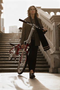 Donna in piedi con la bici elettrica pieghevole OneSport OT02 al chiuso