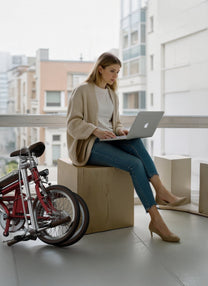 Persona seduta accanto alla bici elettrica pieghevole OneSport OT02 in città