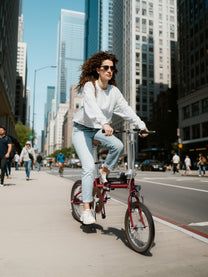 Donna alla guida della bici elettrica pieghevole OneSport OT02 in città
