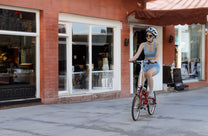 Donna alla guida della bici elettrica pieghevole OneSport OT02 in una strada