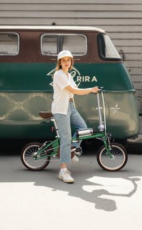 Donna in piedi con la bici elettrica pieghevole OneSport OT02 in una strada