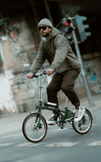 Uomo alla guida della bici elettrica pieghevole OneSport OT02 Pro in colore verde in una strada