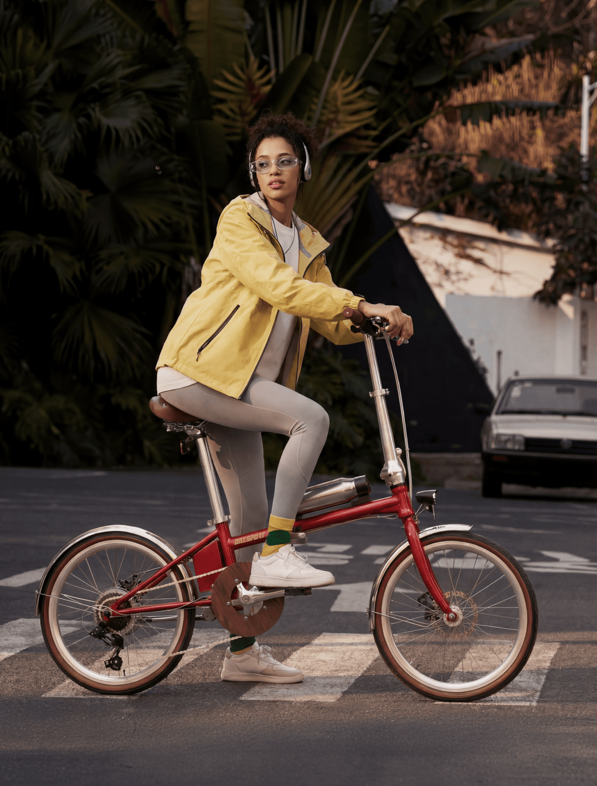 Donna alla guida della bici elettrica pieghevole OneSport OT02 Pro in colore rosso in una strada