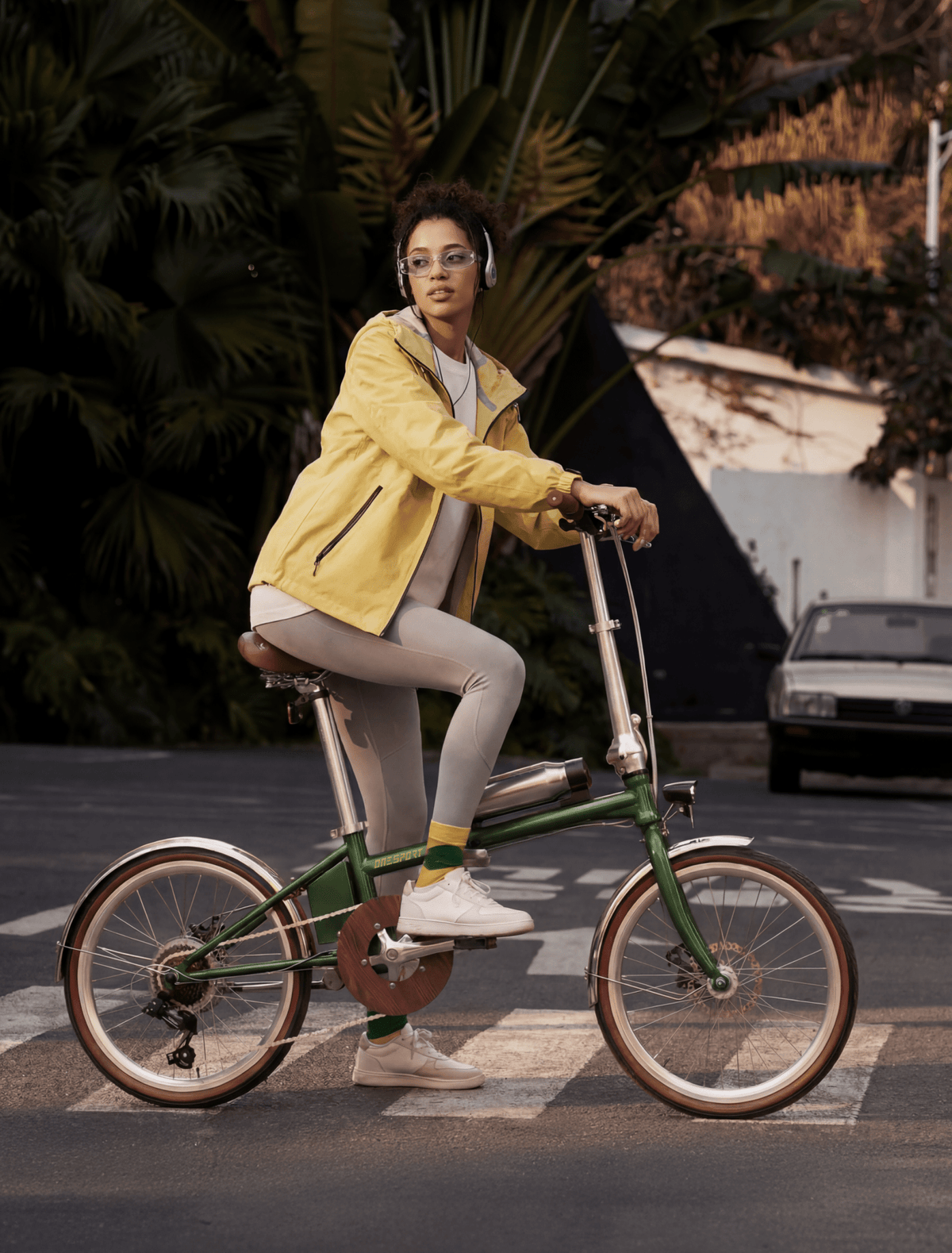 Donna alla guida della bici elettrica pieghevole OneSport OT02 Pro in colore verde in una strada