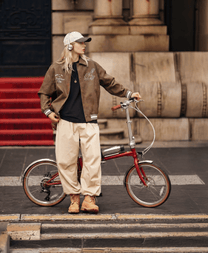 Uomo in piedi con la bici elettrica pieghevole OneSport OT02 Pro in colore rosso in una strada