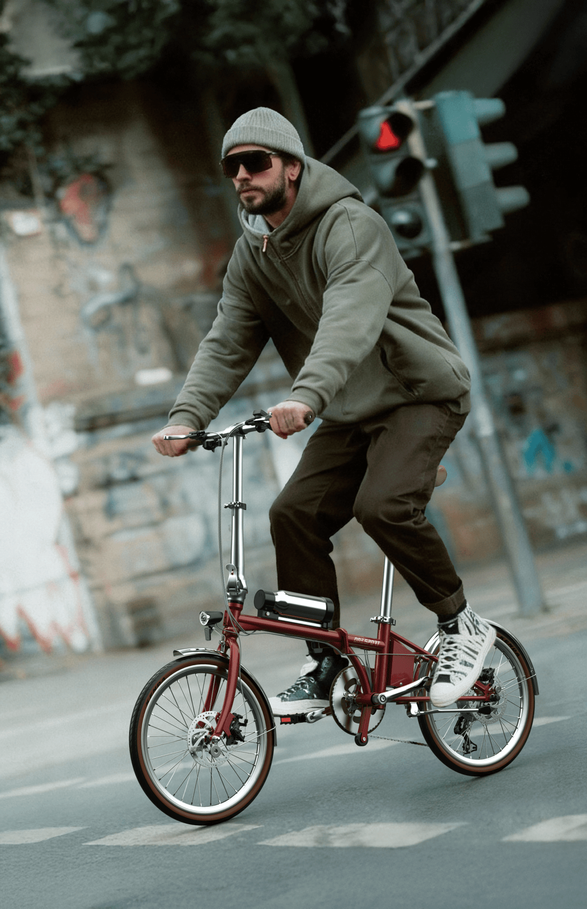 Uomo alla guida della bici elettrica pieghevole OneSport OT02 Pro in colore rosso in una strada