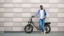 Uomo in piedi con la fat bike elettrica OneSport OT08 Pro in colore grigio in una strada