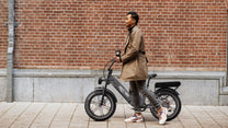 Donna in piedi con la fat bike elettrica OneSport OT08 Pro in colore grigio in una strada