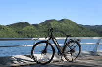 Bici elettrica OneSport OT12 vista di tre quarti in colore nero in riva al mare