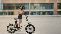 Donna in piedi con la bici elettrica pieghevole OneSport OT16-2 in colore beige in città