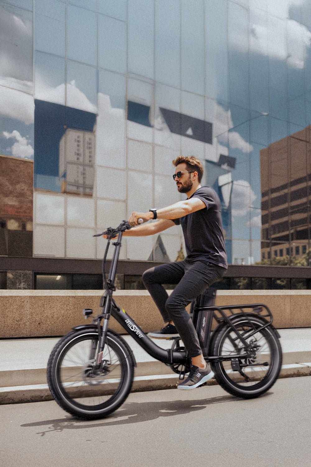 Uomo alla guida della bici elettrica pieghevole OneSport OT16-2 in colore nero in una strada
