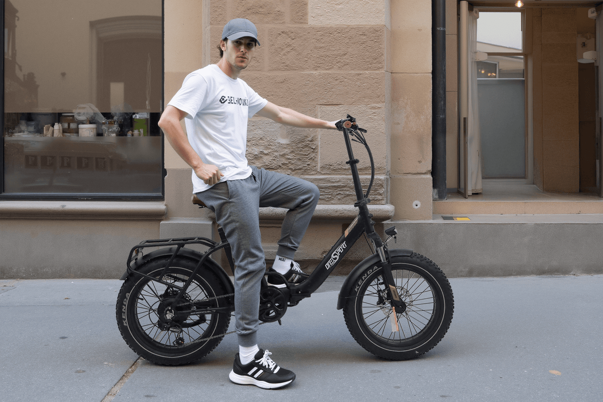 Uomo alla guida della fat bike elettrica pieghevole OneSport OT16 Max in colore nero in una strada