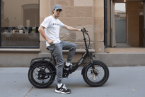 Uomo alla guida della fat bike elettrica pieghevole OneSport OT16 Max in colore nero in una strada