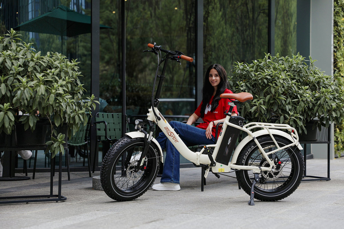 Donna in sella alla fat bike elettrica pieghevole OneSport OT16 Max in colore beige in una strada
