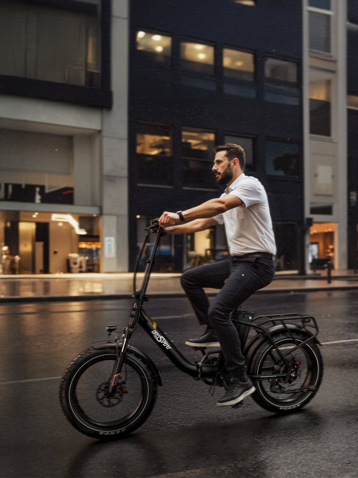 Uomo alla guida della fat bike elettrica pieghevole OneSport OT16 Max in colore nero in un ambiente serale