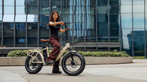 Donna in piedi con la fat bike elettrica pieghevole OneSport OT16 Max in colore beige in città