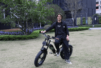 Uomo in piedi con la fat bike elettrica OneSport W66 su un prato