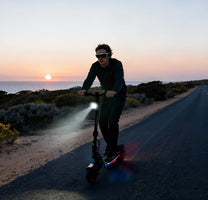 Persona alla guida del monopattino elettrico OOTD SR1 al tramonto
