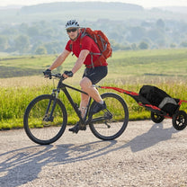 Persona in bici che traina il carrello da traino Smart su una strada di campagna