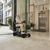 Donna anziana seduta sullo scooter per disabili Sweetrich Air Traveller al chiuso