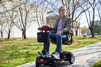 Uomo in sella allo scooter per disabili Sweetrich S1 Sport in un parco