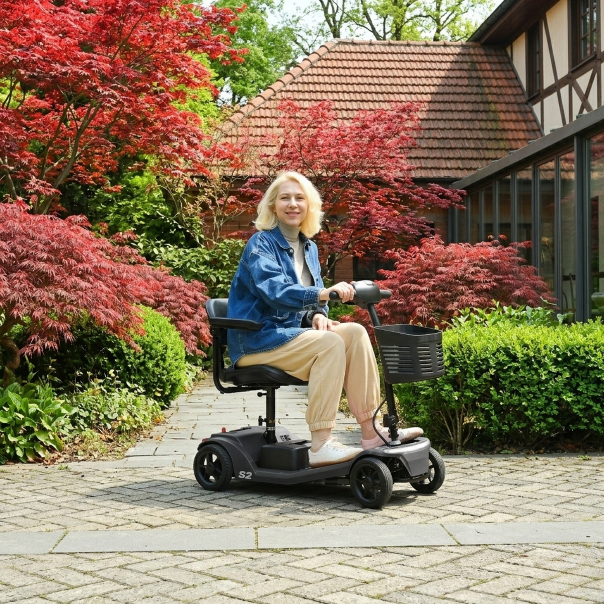Donna anziana seduta sullo scooter per disabili Sweetrich S2 in un giardino