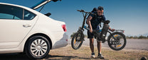 Uomo in piedi con la bici elettrica pieghevole VARUN C20-1 Pro in colore nero