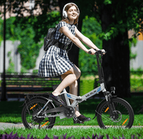 Donna alla guida della bici elettrica pieghevole VARUN C20-1 Pro in colore bianco in un parco