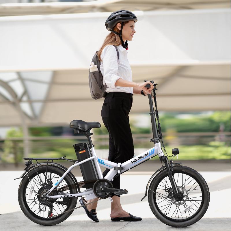Donna in piedi con la bici elettrica pieghevole VARUN C20-1 Pro in colore bianco con il casco