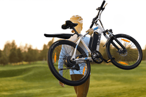 Persona in piedi con la mountain bike elettrica VARUN M24-1 in colore bianco su un prato