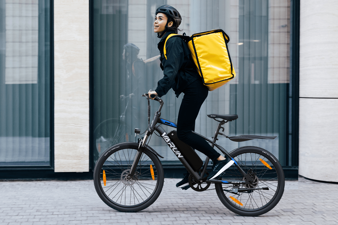 Persona alla guida della mountain bike elettrica VARUN M24-1 in colore nero con il casco in città