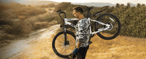 Uomo in piedi con la mountain bike elettrica VARUN M24-1 in colore bianco su un prato